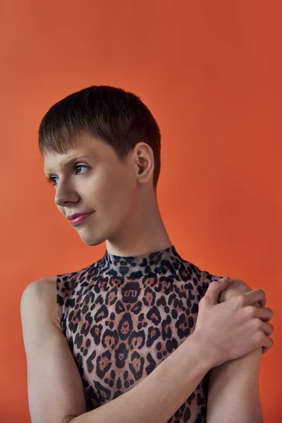 Moda queer, alegre pessoa não binária sorrindo e olhando para longe, pano de fundo laranja, impressão animal — Fotografia de Stock