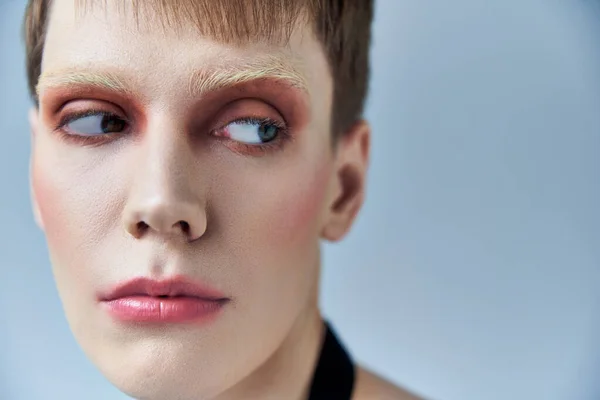 Close, andrógino pessoa com maquiagem, fundo cinza, beleza e visagem, queer, retrato — Fotografia de Stock