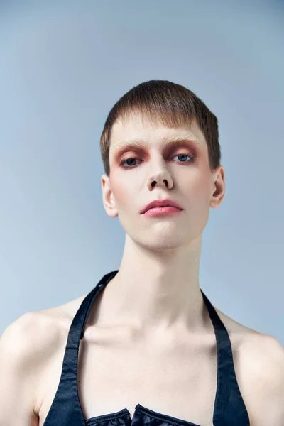 Porträt, androgyne Person mit Make-up, grauem Hintergrund, Schönheit und Visage, queer, Blick in die Kamera — Stockfoto