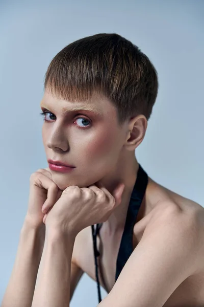 Queer model looking at camera on grey backdrop, style de personne androgyne, portrait, identité — Photo de stock