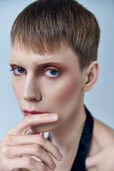 Queer avec maquillage regardant loin sur fond gris, androgyne, portrait, identité — Photo de stock