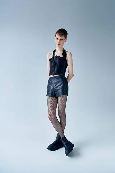 Modelo andrógino em espartilho preto e shorts de pé em cinza, lgbt, moda queer, comprimento total — Fotografia de Stock