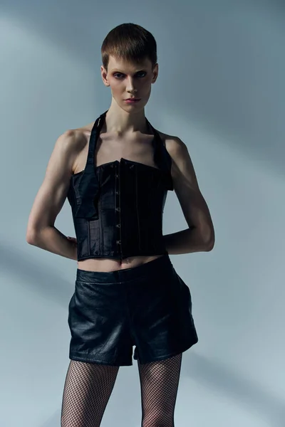 Androgyne Person in Korsett und Netzstrumpfhose posiert auf grau, lgbt, concept, queer fashion — Stockfoto