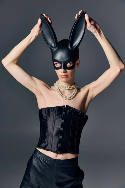 Queer persona in corsetto toccare bdsm coniglietto maschera su grigio, moda, provocatorio, lgbtq, androgino — Foto stock