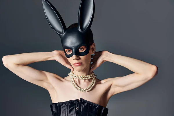 Queer person in corset and black bdsm bunny mask looking at camera on grey, androgynous, fashion — Stock Photo