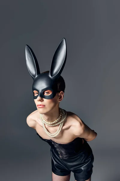 Queer persona in corsetto e bdsm coniglietto maschera in posa su grigio, androgino, moda, guarda la fotocamera — Foto stock