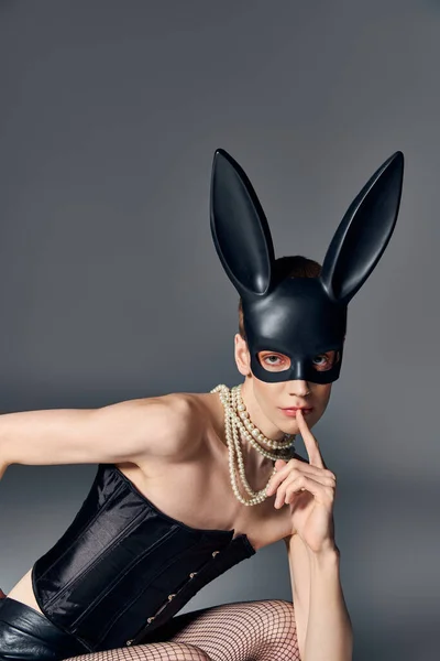 Olhar ousado, pessoa queer provocante em espartilho posando em bdsm máscara de coelho em cinza, moda nervosa, estilo — Fotografia de Stock