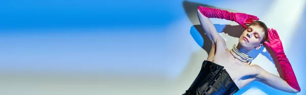 Von oben, queeres Modell in Korsett und rosa Handschuhen auf blauem Hintergrund liegend, geschlossene Augen, Banner — Stockfoto