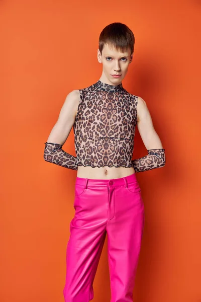 Modelo genderfluid em roupa de impressão animal posando em pano de fundo laranja, pessoa queer, moda e estilo — Fotografia de Stock
