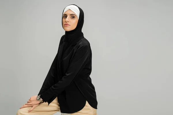 Muslim businesswoman in hijab and stylish casual clothes looking at camera on grey, headshot — Stock Photo