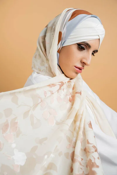 Retrato de bela mulher muçulmana com maquiagem vestindo elegante cachecol de seda em bege, moda islâmica — Fotografia de Stock