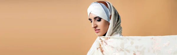 Portrait of graceful muslim woman with makeup, in stylish silk scarf on beige, elegance, banner — Stock Photo