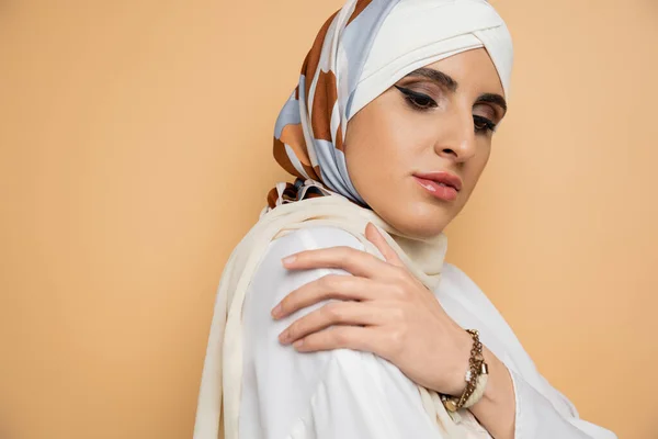 Schöne muslimische Frau mit Make-up posiert in Seide elegantes Kopftuch und weiße Bluse auf beige — Stockfoto