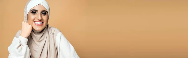 Fröhliche muslimische Frau in weißem Sweatshirt und Hijab mit Blick in die Kamera auf beige, persönlicher Stil, Banner — Stockfoto