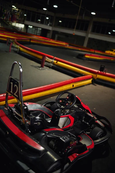Diseño de coche de carreras rojo en el interior del circuito de karts de interior, vehículo de carreras de motor con número doce - foto de stock