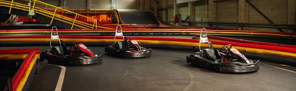Tres coches de carreras en el interior del circuito de karts de interior, vehículos de carreras de motor, karting para carreras de velocidad, bandera - foto de stock