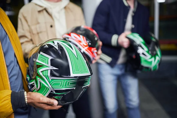 Cropped african american man holding helmet near friends inside of indoor racing track, karting — Stock Photo