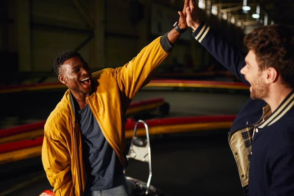 Uomo afroamericano eccitato dando il cinque ad un amico all'interno della pista di karting, vincere — Foto stock