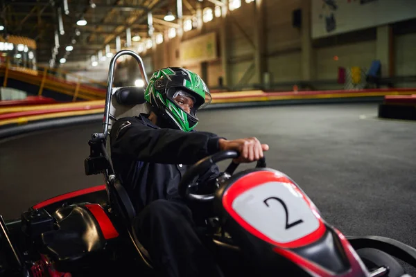 Go kart speed drive, conductor afroamericano enfocado en casco en circuito, karting motorsport - foto de stock