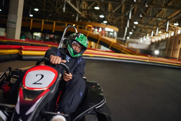 Go cart speed drive, conductor afroamericano en casco en circuito, karting concepto de automovilismo - foto de stock