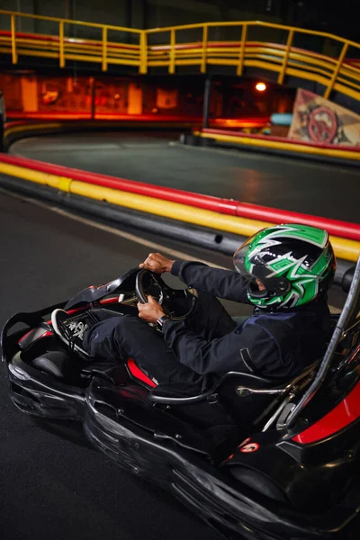 Африканский американский водитель в шлеме держа руль картинга гоночный автомобиль, скорость привода — стоковое фото