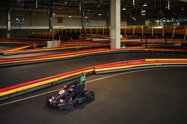 Speed drive, african american man in go-kart on circuit, racing inside of indoor karting track — Stock Photo