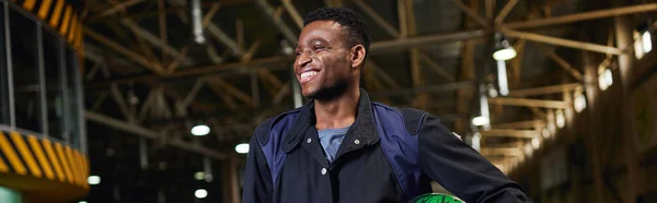Fröhlicher afrikanisch-amerikanischer Mann in Sportbekleidung, der neben dem Go-Kart auf der Kartbahn steht, horizontales Banner — Stockfoto