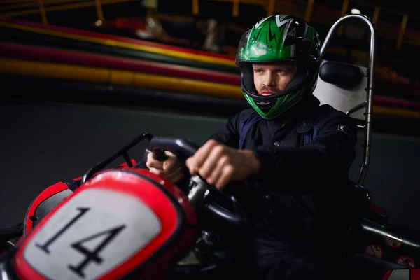 Homem em capacete e sportswear condução go kart no circuito interno, adrenalina e conceito de automobilismo — Fotografia de Stock
