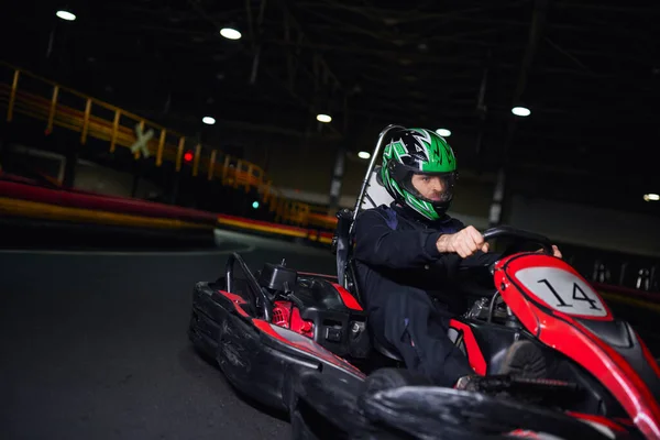 Focused racer in helmet and sportswear driving go kart on indoor circuit, adrenaline concept — Stock Photo