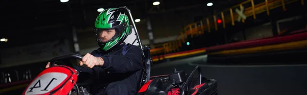 Focused racer in helmet and sportswear driving go kart on indoor circuit, adrenaline concept, banner — Stock Photo