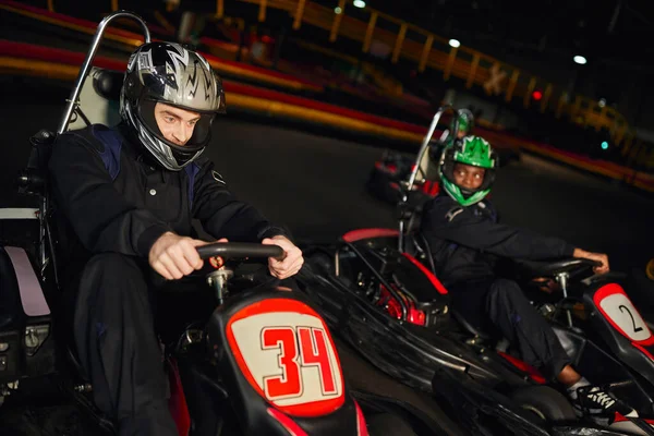 Pessoas multiétnicas focadas dirigindo carro kart go no circuito interno, corrida de velocidade e competição — Fotografia de Stock