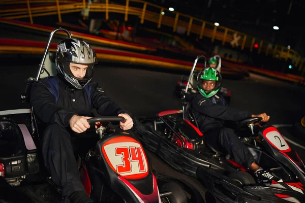Competidores multiculturais dirigindo ir kart no circuito interno, corrida de velocidade e automobilismo — Fotografia de Stock