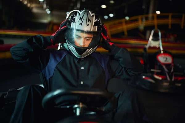Conductor quitándose el casco después de las carreras en ir coche de karting en el circuito, la velocidad de conducción y el concepto de automovilismo - foto de stock