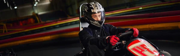 Focused speed racer in helmet driving go kart car on indoor circuit, motorsport competition, banner — Stock Photo