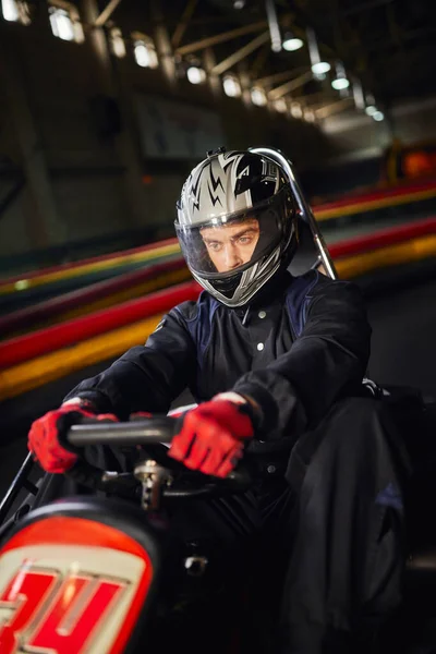 Концентрированный гонщик в шлеме вождения go kart car на крытой трассе, концепция автоспортивных соревнований — стоковое фото