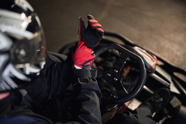 Vista superior de go kart piloto no capacete vestindo luvas esportivas vermelhas, preparando-se para o conceito de competição — Fotografia de Stock