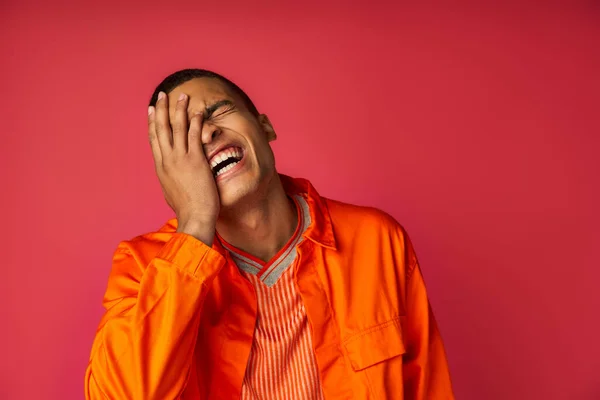 Afrikanisch-amerikanisches verschleierndes Gesicht und Lachen, Aufregung, orangefarbenes Hemd, trendiger roter Hintergrund — Stockfoto