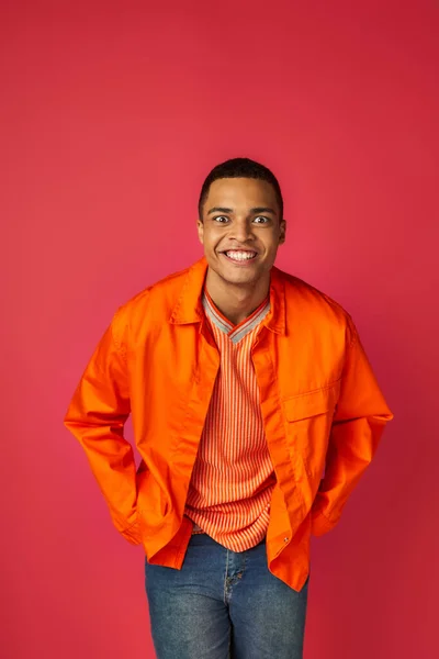 Allegro, divertente uomo africano americano, espressione faccia pazza, guardando la fotocamera su rosso, camicia arancione — Foto stock