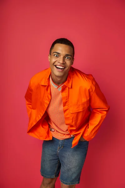 Super alegre e engraçado homem americano africano, expressão rosto louco olhando para a câmera no fundo vermelho — Fotografia de Stock