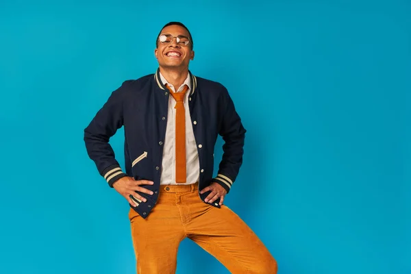 Carefree and stylish african american student with radiant smile looking at camera on blue — Stock Photo