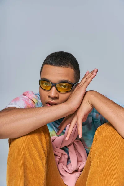 Homme afro-américain à la mode en lunettes de soleil à la mode et t-shirt tie-dye regardant caméra sur gris — Photo de stock
