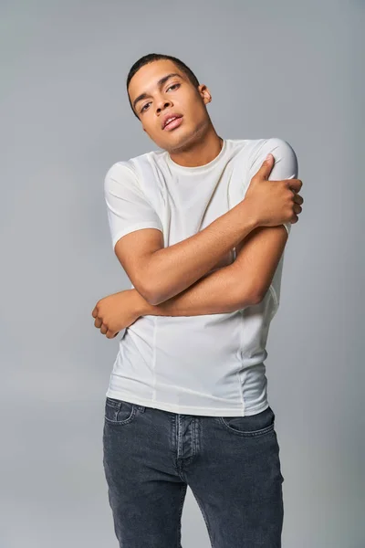 Tendance de la mode, jeune afro-américain en t-shirt et jeans regardant la caméra sur gris — Photo de stock