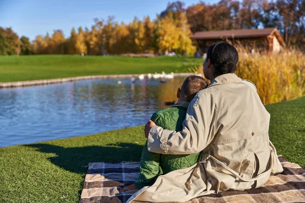 Bonding between mother and child, positive african american woman hugging boy, pond, swans — Stock Photo