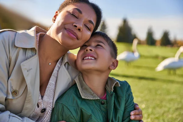 Retrato de mujer y niño afroamericanos positivos, madre e hijo abrazando, vinculación y amor - foto de stock