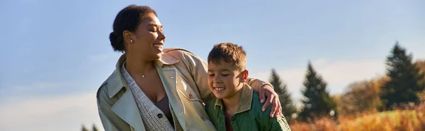 Mère afro-américaine positive étreignant avec son fils, saison d'automne, vêtements de dessus, lien de famille, bannière — Photo de stock