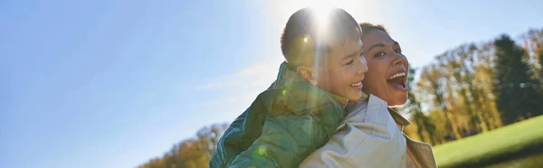 Candid, free spirit, excited mother piggybacking son, african american woman and boy, autumn, banner — Stock Photo