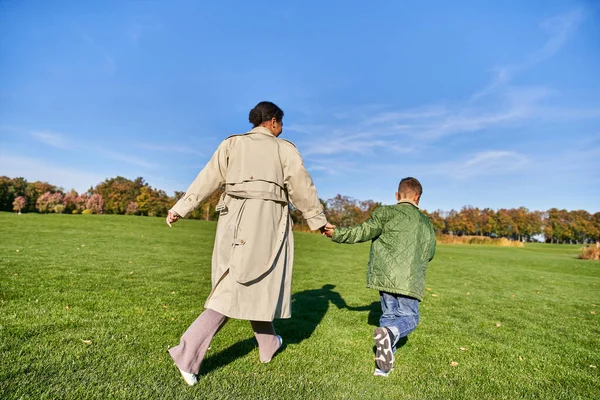 Brincalhão, mulher americana africana correndo junto com o filho no parque, sincero, dia ensolarado no outono — Fotografia de Stock