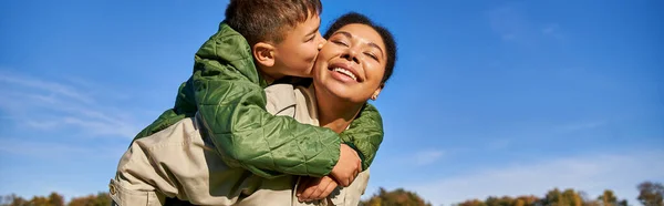 Мальчик целует щеку мамы, африканская американская семья, веселится вместе, связывает концепцию, баннер — стоковое фото