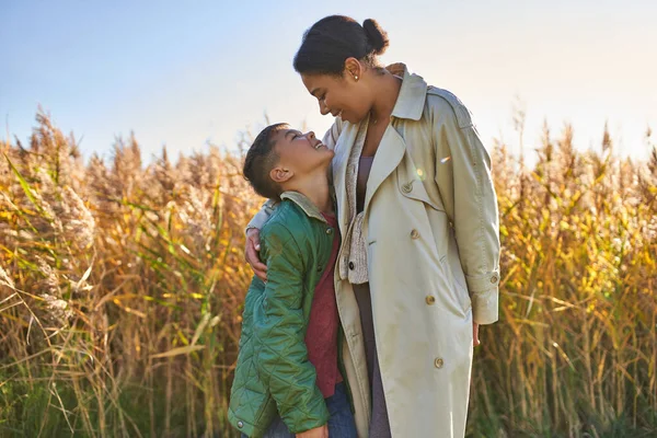 Motherly love, african american mother in autumnal clothes embracing son, fall season, outerwear — Stock Photo