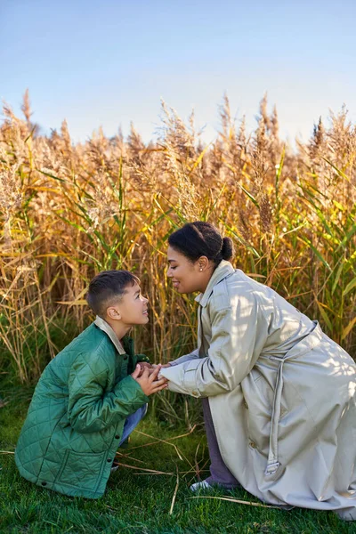 Motherly love, african american mother in autumnal clothes holding hands of son, fall season — Stock Photo
